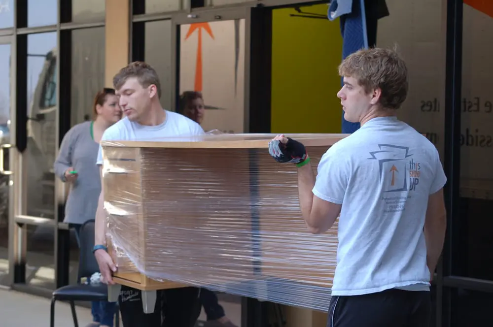 two movers carrying a desk onto a moving truck