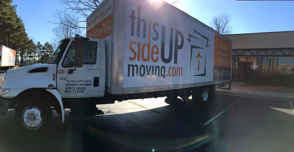 a white moving truck parked in front of a commercial building in Madison Alabama